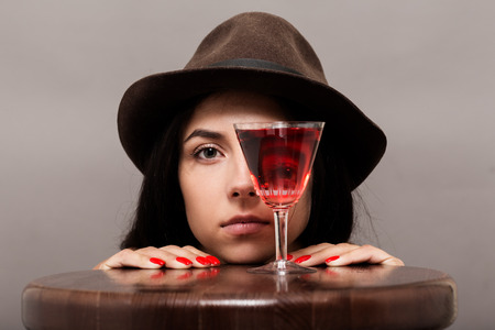 girl looks at camera through wineglass on gray backgroundの写真素材