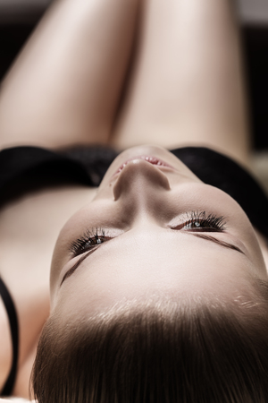 sensual beautiful girl in lingerie lying on bed looking upの写真素材
