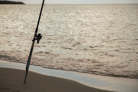 rod on the sea coast evening fishing at golden sunsetの写真素材