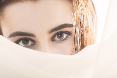 sad woman looking at camera over veil on white background with copy spaceの写真素材