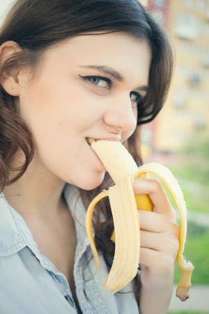 sensual happy young woman eats banana looking at cameraの写真素材