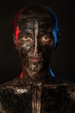 woman with black dirty smeared make up on black backgroundの写真素材