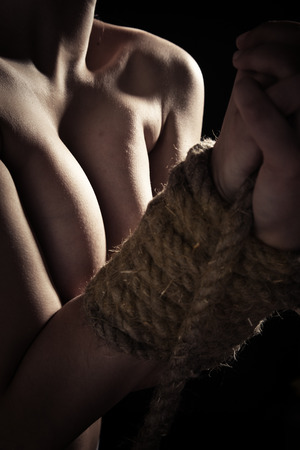 unrecognizable young naked woman with tied hands on black backgroundの写真素材