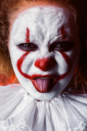 angry evil clown, show tongue looking at camera close upの写真素材