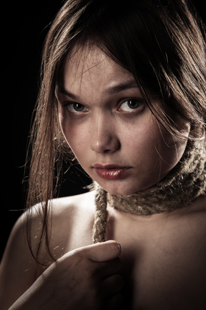 sad young woman with tied neck on black background looking at cameraの写真素材
