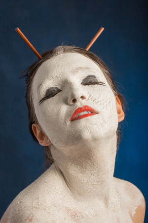 girl with white cracked make-up on blue backgroundの写真素材