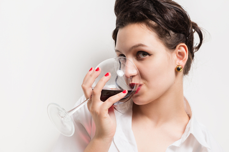 young beautiful woman drinking red wine on white backgroundの写真素材