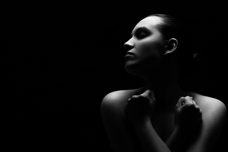 sad pensive woman on black background, monochrome image with copy spaceの写真素材