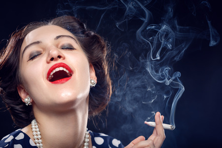 blond young woman smoking joint on black backgroundの写真素材