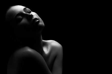 sad woman with closed eyes relax sitting on black background, monochrome imageの写真素材