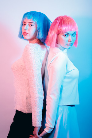 two sensual girls in wigs on multicolor background の写真素材