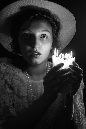 scared young woman with candles in dark looking at cameraの写真素材