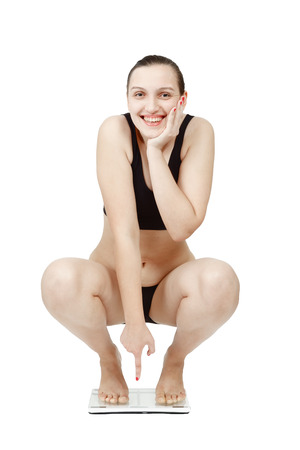 thick overweight woman on scales isolated over white background smilingの写真素材