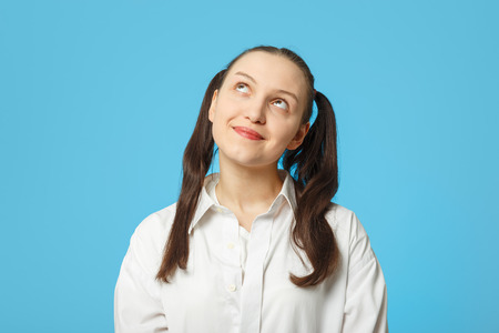 Sly girl thinker on blue background looking upの写真素材