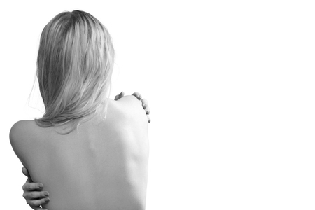nude young blond young woman hugging herself isolated on white background with copy space, monochromeの写真素材