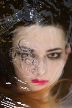 beautiful woman soaks in the warm water and looking at camera, blurred imageの写真素材