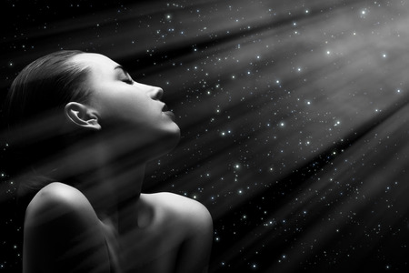 sensual aroused woman with closed eyes on stars background with light rays, monochromeの写真素材
