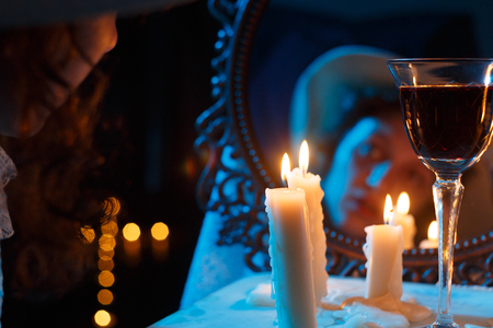 mirror with blurred female face candles and red wineの写真素材