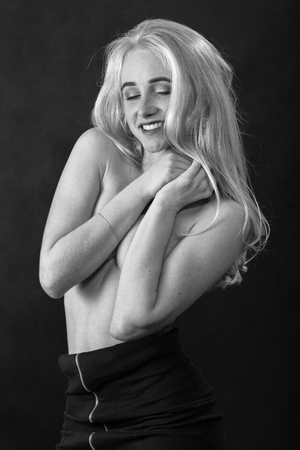 beautiful young woman covering her body on black backgroundの写真素材