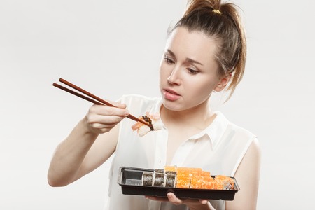 fun young woman eating sushi on white backgroundの写真素材