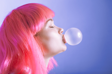 girl in a wig inflates a bubble from chewing gumの写真素材