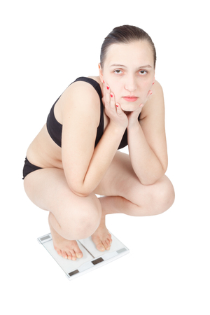 thick overweight woman on scales isolated over white backgroundの写真素材