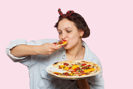 happy woman with pizza on pink background eatsの写真素材