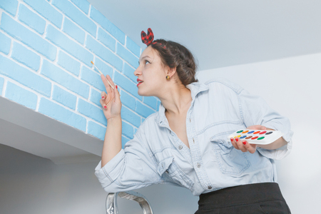 woman the artist paints bricks on a wallの写真素材