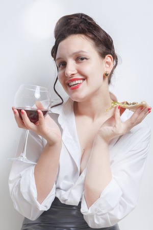 happy woman with pizza and red wine on white background sitting, looking at cameraの写真素材