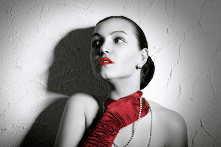 Beauty Fashion Glamorous Model female Portrait. Vintage Style Mysterious Woman Wearing Red Glamour Gloves. Jewelry. Holiday Hairstyle and Make-upの写真素材