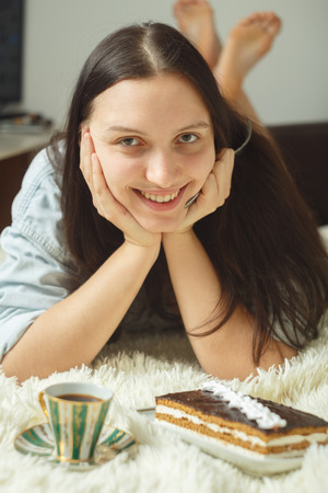 happy young woman with sweet cake on bed smilingの写真素材