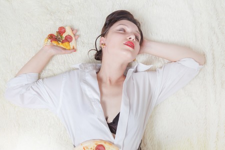 beautiful overeat businesswoman lying with pizza piecesの写真素材