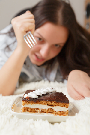 hungry happy young woman with sweet cake on bed smilingの写真素材