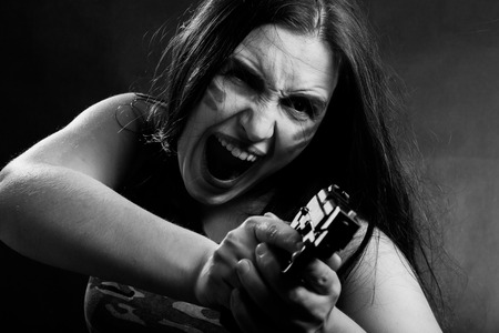 screaming young woman with gun aiming on red background, monochrome