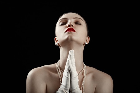 sensual luxury young woman with closed eyes in white gloves on black background prays