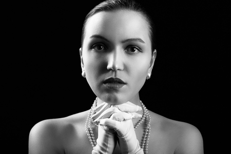 sad luxury young woman in white gloves on black background looking at camera, monochromeの写真素材