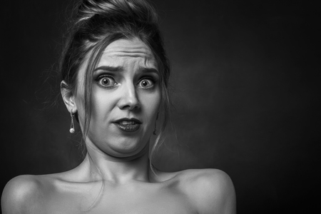 shocked fun girl on black background with copy space looking at camera, monochromeの写真素材