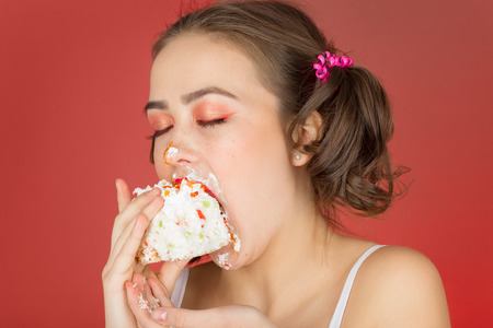 hungry dirty girl with sweet dessert on red backgroundの写真素材