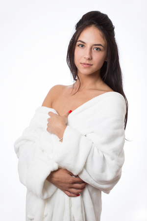 pretty brunette girl in bathrobe on white background looking at cameraの写真素材