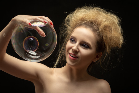 girl plays with big soap bubbles on black backgroundの写真素材