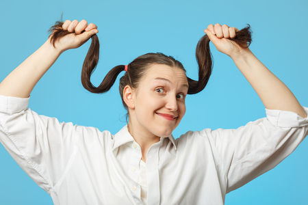 brunette woman shows her hair on blue background smilingの写真素材