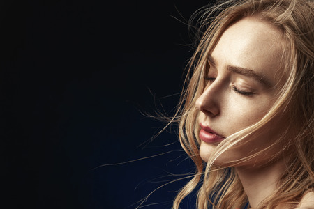 sensual woman with closed eyes and bare shoulders on black background with copy space