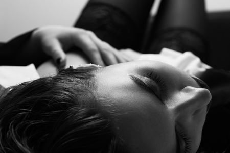 sensual beautiful woman in stockings lying in bed, monochromeの写真素材
