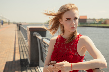 pretty serious girl with smartphone on embankment waiting looking asideの写真素材