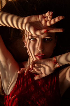 sensual girl lying on bed in sunlight with blinds shadowsの写真素材