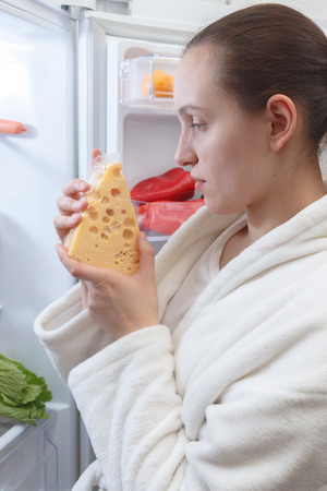 serious woman with cheese near opened refrigeratorの写真素材