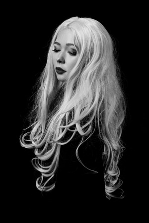 beautiful female with long curly blond hairs on black background, monochromeの写真素材
