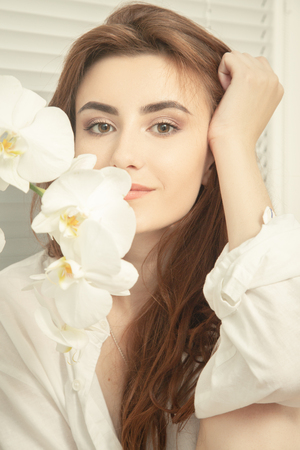 happy beautiful young woman smell white orchid looking at camera smilingの写真素材