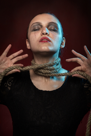 serious woman with rope on her neck on red backgroundの写真素材