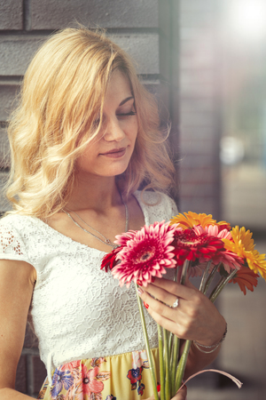 pensive young blond woman with bouquet of flowers looking at cameraの写真素材
